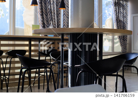 Modern Cafe Interior with Round Wooden Table Standing Around Pillar and Black Stools Modern Cafe Interior with Round Wooden Table Standing Around Pillar and Black Stools 141706159