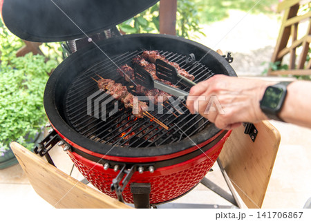 grilled meat skewers cooking on ceramic kamado barbecue grill grilled meat skewers cooking on ceramic kamado barbecue grill 141706867