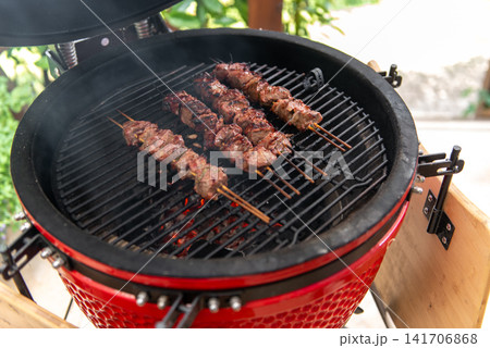 grilled meat skewers cooking on ceramic kamado barbecue grill grilled meat skewers cooking on ceramic kamado barbecue grill 141706868