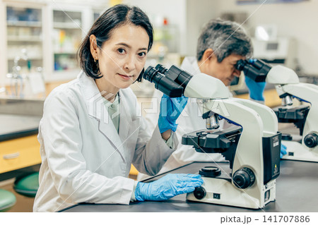 実験室で顕微鏡を使用して研究を行う研究者 実験室で顕微鏡を使用して研究を行う研究者 141707886