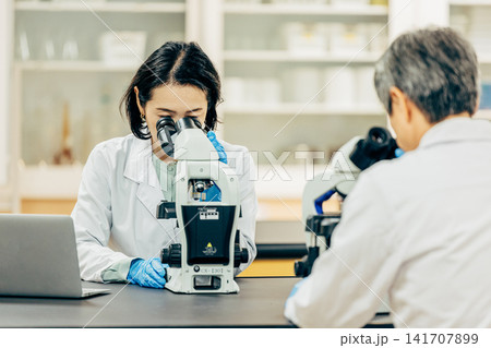 実験室で顕微鏡を使用して研究を行う研究者 実験室で顕微鏡を使用して研究を行う研究者 141707899