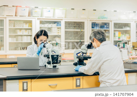 実験室で顕微鏡を使用して研究を行う研究者 実験室で顕微鏡を使用して研究を行う研究者 141707904