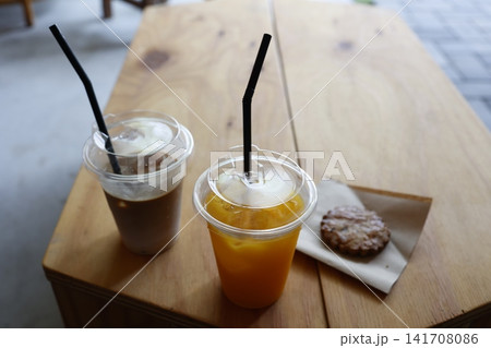 カフェ店内のドリンクとクッキー。オレンジジュースとコーヒー。木製テーブル カフェ店内のドリンクとクッキー。オレンジジュースとコーヒー。木製テーブル 141708086