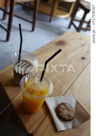 カフェ店内のドリンクとクッキー。オレンジジュースとカフェオレ。木製テーブル カフェ店内のドリンクとクッキー。オレンジジュースとカフェオレ。木製テーブル 141708087