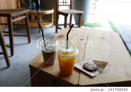 カフェ店内のドリンクとクッキー。オレンジジュースとコーヒー。木製テーブル カフェ店内のドリンクとクッキー。オレンジジュースとコーヒー。木製テーブル 141708088