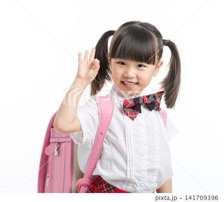 Cheerful little girl in school uniform making OK sign with hand, successful education concept. 141709396