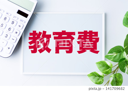 教育費の文字のホワイトボードと白い電卓 教育費の文字のホワイトボードと白い電卓 141709682