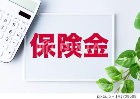 保険金の文字のホワイトボードと白い電卓 保険金の文字のホワイトボードと白い電卓 141709689