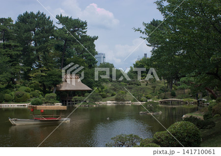 Scenic view of a tea house and a traditional boat in a Japanese park. Scenic view of a tea house and a traditional boat in a Japanese park. 141710061
