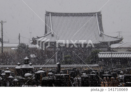 Close-up of a heavy snow falling over a dark Buddhist temple in front of a cementery. Close-up of a heavy snow falling over a dark Buddhist temple in front of a cementery. 141710069