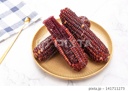 boiled black sticky corn on cobs served on a plate isolated on white background boiled black sticky corn on cobs served on a plate isolated on white background 141711273