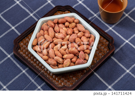 thirteen spice peanuts served in a bowl on a wooden tray thirteen spice peanuts served in a bowl on a wooden tray 141711424