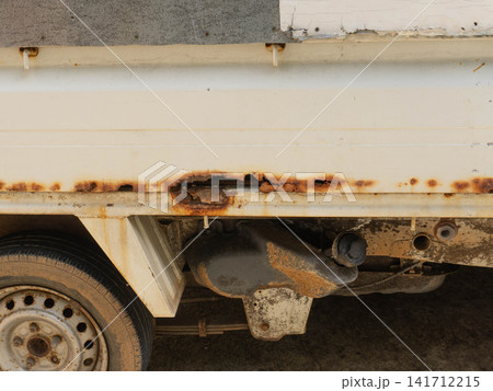 Severe rust damage and corrosion holes on the side frame of an old truck body 141712215