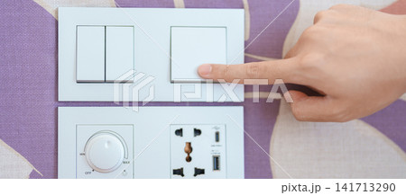 finger pushing for turn on light switch on white wall at home room. Woman hand turn off lighting Switch. Energy Saving, energy power control, electrical, eco environment, and lifestyle concept finger pushing for turn on light switch on white wall at home room. Woman hand turn off lighting Switch. Energy Saving, energy power control, electrical, eco environment, and lifestyle concept 141713290