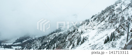 Snow blankets mountains under dense fog providing a serene view Snow blankets mountains under dense fog providing a serene view 141713311