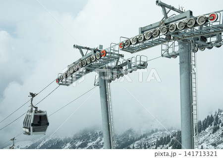 Cable car transports passengers through misty mountain landscape Cable car transports passengers through misty mountain landscape 141713321