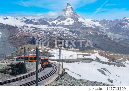 Iconic Matterhorn Mountain with Gornergrat Railway Train in Zermatt, Switzerland, Snow Capped Alpine Peak under Blue Sky, Famous Swiss Alps Landmark landscape and popular European Travel Destination Iconic Matterhorn Mountain with Gornergrat Railway Train in Zermatt, Switzerland, Snow Capped Alpine Peak under Blue Sky, Famous Swiss Alps Landmark landscape and popular European Travel Destination 141713399
