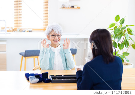 出張買取　自宅で宝石の鑑定をしてもらっているシニア女性　 141713892