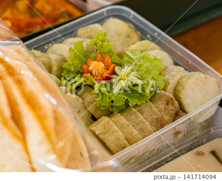 Traditional Indonesian lontong rice cake served in takeaway container with lettuce and chili garnish, authentic Asian street food concept Traditional Indonesian lontong rice cake served in takeaway container with lettuce and chili garnish, authentic Asian street food concept 141714094