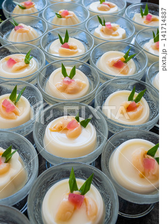 Elegant coconut dessert cups garnished with tropical fruit and pandan leaves. Ideal for luxury buffet, catering, restaurant, hospitality, wedding, and celebration concepts. Elegant coconut dessert cups garnished with tropical fruit and pandan leaves. Ideal for luxury buffet, catering, restaurant, hospitality, wedding, and celebration concepts. 141714887