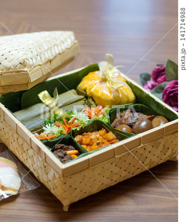 Traditional Indonesian food hamper with lontong, beef rendang, spicy potatoes, eggs and crackers presented in a bamboo basket for Ramadan, Eid, catering and festive family celebrations. Traditional Indonesian food hamper with lontong, beef rendang, spicy potatoes, eggs and crackers presented in a bamboo basket for Ramadan, Eid, catering and festive family celebrations. 141714988