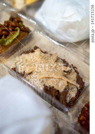 Traditional Indonesian gudeg with creamy kuah areh coconut sauce served with assorted side dishes in a clear takeaway food container. Traditional Indonesian gudeg with creamy kuah areh coconut sauce served with assorted side dishes in a clear takeaway food container. 141715156