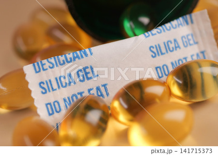 Silica gel packet with capsules and bottle on a surface Silica gel packet with capsules and bottle on a surface 141715373