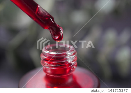 Close-Up Red Cosmetic Serum Dropper Dripping Into Glass Bottle For Beauty And Skincare Close-Up Red Cosmetic Serum Dropper Dripping Into Glass Bottle For Beauty And Skincare 141715377