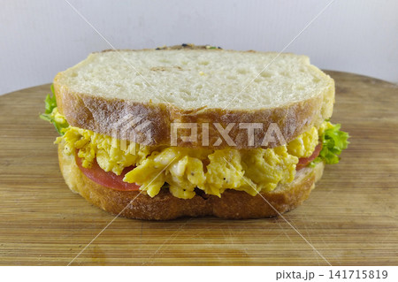 Fresh egg sandwich with ham lettuce and tomato on wooden board isolated on white background breakfast concept. Fresh egg sandwich with ham lettuce and tomato on wooden board isolated on white background breakfast concept. 141715819