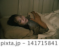 ベッドでスマホを見る若い女性 141715841