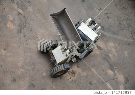 Aerial view of construction site where a front loader is loading soil, rocks, and debris into a dump truck, industrial work, excavation, and earthmoving processes 141715957