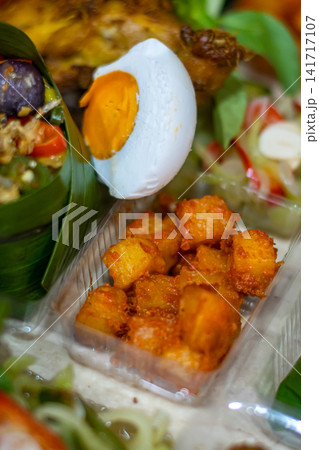 Traditional Indonesian Kentang Balado featuring crispy fried potatoes, salted egg, banana leaf rice, sambal and authentic Indonesian side dishes. Traditional Indonesian Kentang Balado featuring crispy fried potatoes, salted egg, banana leaf rice, sambal and authentic Indonesian side dishes. 141717107
