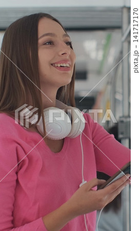 Vertical video. Young woman passenger enjoying trip at the public transport, standing with smartphone in the modern tram. Vertical video. Young woman passenger enjoying trip at the public transport, standing with smartphone in the modern tram. 141717170