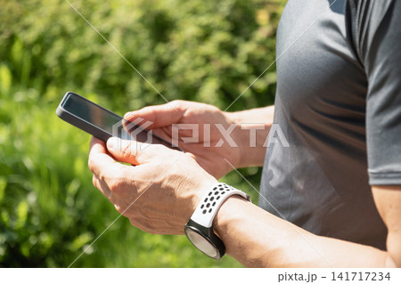 Close up of man using smartphone outdoors after cycling workout Close up of man using smartphone outdoors after cycling workout 141717234