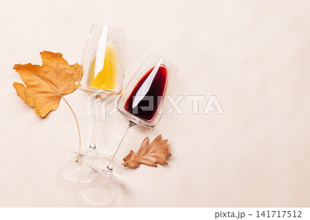 Wine glasses with autumn leaves on beige background Wine glasses with autumn leaves on beige background 141717512