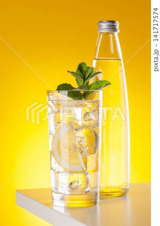 Sparkling water with lemon and bottle on yellow background refreshment Sparkling water with lemon and bottle on yellow background refreshment 141717574