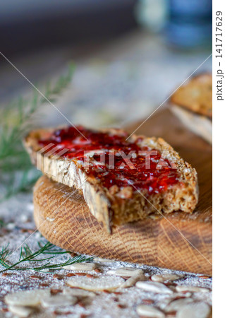 Close-up rustic food still life of sourdough bread with strawberry jam on a wooden board, styled with soft light and a cozy homemade feel. Close-up rustic food still life of sourdough bread with strawberry jam on a wooden board, styled with soft light and a cozy homemade feel. 141717629