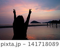 海に沈む夕日と手を広げる女性のシルエット 141718089