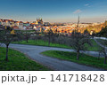 Panoramic Prague cityscape from Petrin Hill with historic red rooftops, green orchards and cathedral towers, capturing scenic spring views of Prague City Czech Republic under clear blue sky 141718428