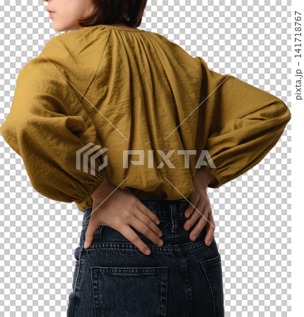 Asian woman wearing mustard blouse shows hand placement across lower back with dark denim garment on isolated background Asian woman wearing mustard blouse shows hand placement across lower back with dark denim garment on isolated background 141718767