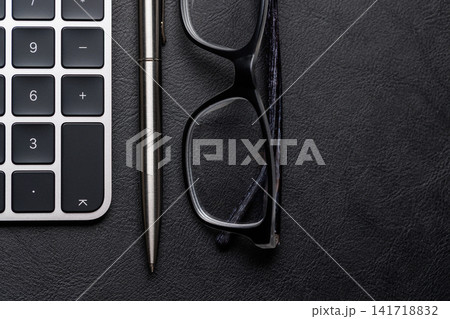 Office supplies on dark leather desk 141718832