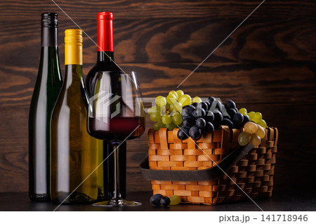 Red and white wine bottles with a glass and basket of fresh grapes Red and white wine bottles with a glass and basket of fresh grapes 141718946