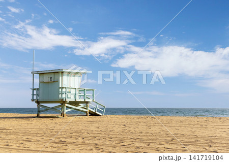 Empty sandy beach with lifeguard tower under blue sky Empty sandy beach with lifeguard tower under blue sky 141719104