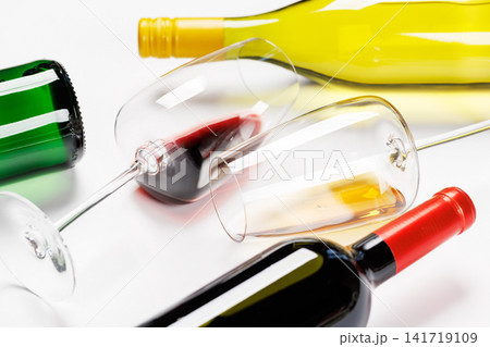 Wine glasses with red and white wine and bottles lying on white background Wine glasses with red and white wine and bottles lying on white background 141719109