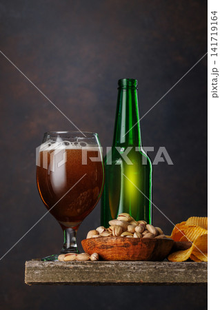 Beer glass with foam and bottle with pistachios Beer glass with foam and bottle with pistachios 141719164