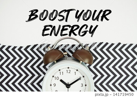 Boost Your Energy text written on paper rip with alarm clock flat lay on black chevron background Boost Your Energy text written on paper rip with alarm clock flat lay on black chevron background 141719450