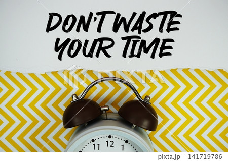 Don't Waste Your Time text written on paper with alarm clock on yellow chevron background Don't Waste Your Time text written on paper with alarm clock on yellow chevron background 141719786