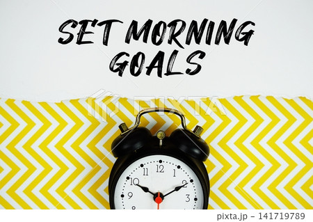 Set Morning Goals text written on paper with alarm clock on yellow chevron background Set Morning Goals text written on paper with alarm clock on yellow chevron background 141719789