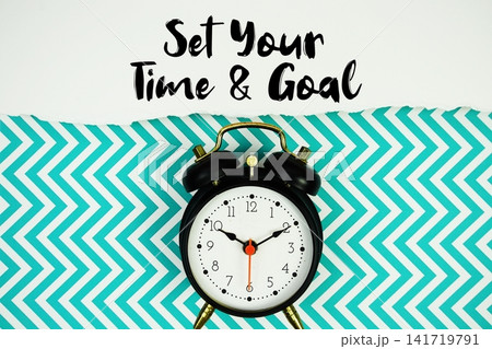 Set Your Time and Goal text written on paper with alarm clock on green chevron background Set Your Time and Goal text written on paper with alarm clock on green chevron background 141719791