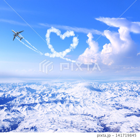 Airplane drawing heart in sky over the mountains. Jet flight route of aircraft in shape of heart. Heart-shaped flight path drawn by plane. Topic of holiday, travel, trip abroad on vacation, tour Airplane drawing heart in sky over the mountains. Jet flight route of aircraft in shape of heart. Heart-shaped flight path drawn by plane. Topic of holiday, travel, trip abroad on vacation, tour 141719845